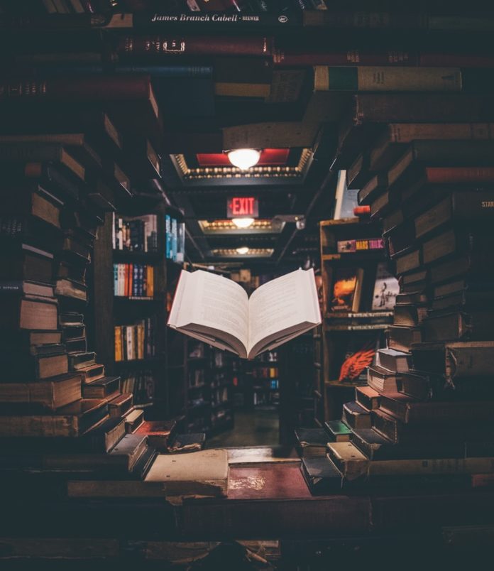 view of floating open book from stacked books in library