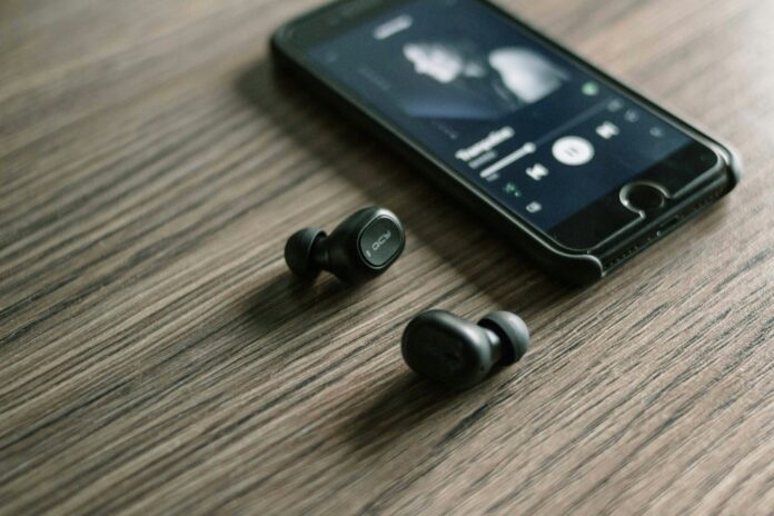 Photo by Zarak Khan Spotify account pair of Bluetooth earphones beside phone